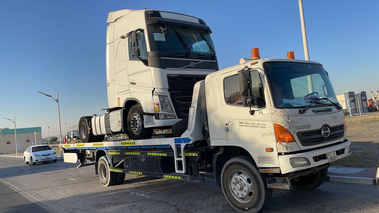 Hino flatbed recovery truck carrying a Volvo